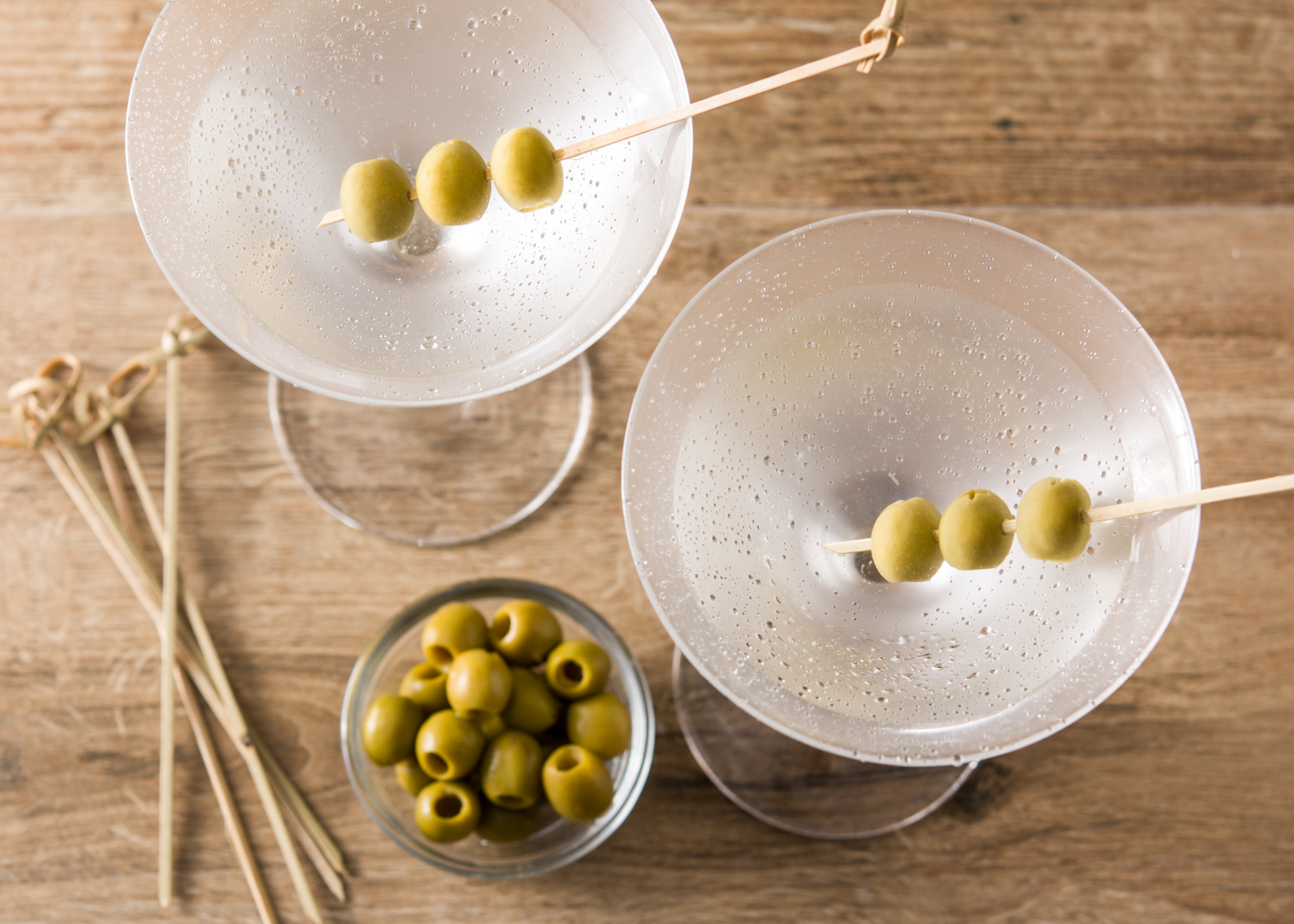 two glasses of dry martini cocktail with olive garnish